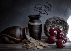Jabłka wysypane z kosza na drewniany blat obok glinianych wazonów