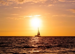 Jacht na pełnym morzu w blasku wschodzącego słońca