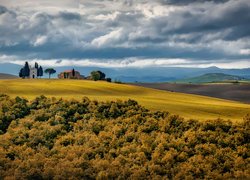 Jesienne drzewa i dom na wzgórzu w Toskanii