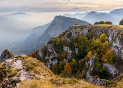 Jesienne drzewa na skałach i mgła nad górami i doliną