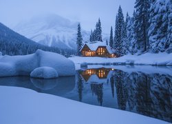 Jezioro Emerald Lake i oświetlony dom na tle gór zimową porą