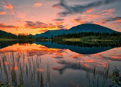 Jezioro i góry pod kolorowym niebem zachodzącego słońca
