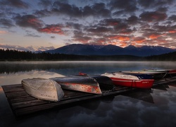 Jezioro o zachodzie słońca i łódki na pomoście