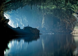 Jezioro płynące przez jaskinię i człowiek na skale