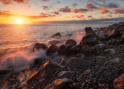 Kamienie i skały na wybrzeżu morza w blasku zachodzącego słońca