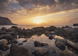 Kamienie na brzegu morza w promieniach zachodzącego słońca