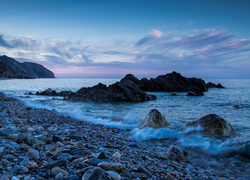 Kamienisty brzeg morza i fale uderzające o skały