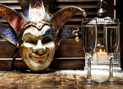 Karnawałowa maska obok kieliszków z szampanem