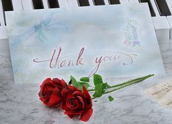 Karteczka z podziękowaniem obok róż i biletów