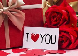 Kartka z napisem I love you obok prezentu i czerwonych róż