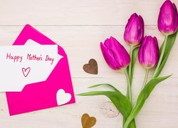 Kartka z życzeniami na Dzień Matki w kopercie obok tulipanów i serduszek