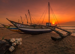 Katamarany na plaży w zachodzącym słońcu