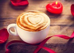 Kawa cappuccino w filiżance obok świeczki w kształcie serca