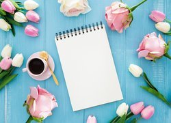 Kawa i notes pośród róż i tulipanów