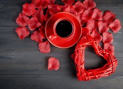 Kawa w czerwonej filiżance obok serca i płatków