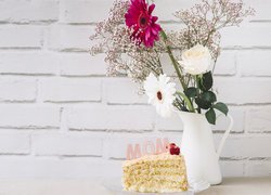 Kawałek tortu obok kwiatów w wazonie na Dzień Matki