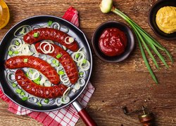 Kiełbasa pieczona,  Patelnia, Cebulka, Musztarda, Keczup, Szczypiorek, Oliwa, Ścierka, Deski