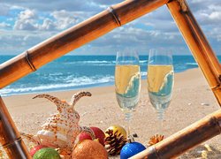 Kieliszki z szampanem obok bombek i muszli na plaży