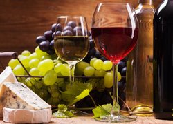 Kieliszki z winem obok kiści winogron i sera