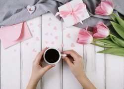 Kobiece dłonie z filiżanką kawy i tulipany