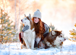 Kobieta i psy husky pozują w śniegu