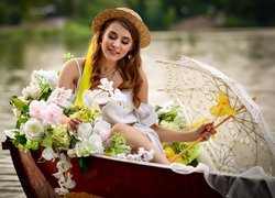 Kobieta na łódce z parasolem i kwiatami