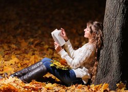 Kobieta pod drzewem czytająca książkę