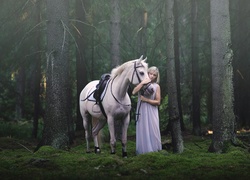 Kobieta przytulająca konia pośród drzew