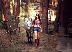 Kobieta spacerująca z koniem po lesie