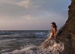 Kobieta - Syrena w spienionych morskich falach przy skale