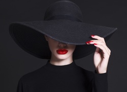 Kobieta w czarnym kapeluszu zasłaniającym twarz