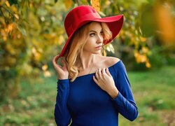 Kobieta w czerwonym kapeluszu i niebieskiej sukience