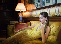Kobieta w eleganckiej sukni odpoczywa na sofie