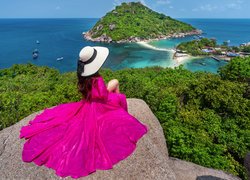 Kobieta w kapeluszu i różowej sukience na skale