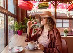 Kobieta w kapeluszu przy kawiarnianym stoliku