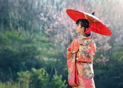Kobieta w kimono trzymająca czerwoną parasolkę