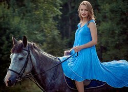 Kobieta w niebieskiej sukience na koniu