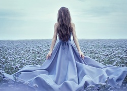 Kobieta w niebieskiej sukience na kwiatowej łące
