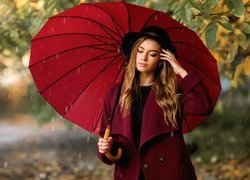 Kobieta w płaszczu pod czerwoną parasolką