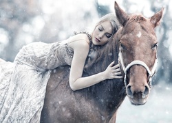 Kobieta w sukience na koniu w zimowym krajobrazie