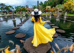 Kobieta w żółtej sukni przy sadzawce w Hotelu Tirtagangga Water Palace Villas na Bali