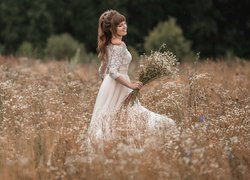 Kobieta z bukietem polnych kwiatów na łące