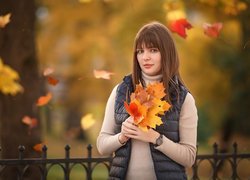Kobieta z jesiennymi liśćmi w dłoniach