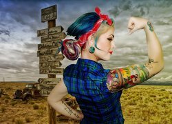 Kobieta z kolorowym tatuażem obok drogowskazu