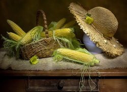 Kolby kukurydzy w koszyku obok kapelusza na dzbanku