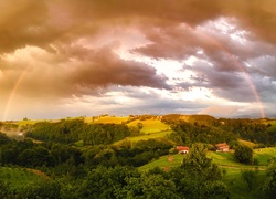 Kolorowa tęcza nad wzgórzem i domami