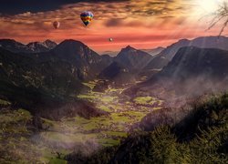 Kolorowe balony nad dolinami i górami w zachodzącym słońcu
