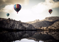 Kolorowe balony nad jeziorem i górami