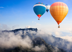Kolorowe balony przelatują nad górami we mgle