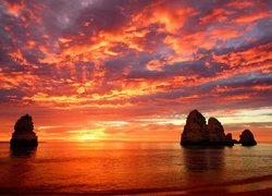 Kolorowe niebo zachodzącego słońca nad skałami w morzu